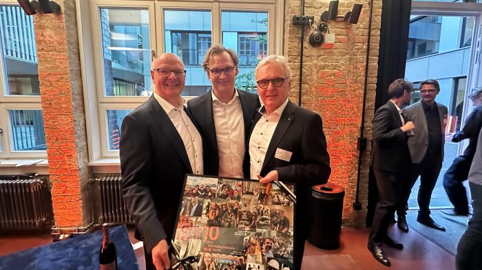 Christian Niehoff (Mitte), geschäftsführender Gesellschafter von BOHNZIRLEWAGEN, mit einem Erinnerungsgeschenk seines Berliner Teams. Gemeinsam mit ihm: die Unternehmensgründer und Namensgeber Prof. Dr.-Ing. Thomas Bohn (links) und Jörg Zirlewagen (rechts)