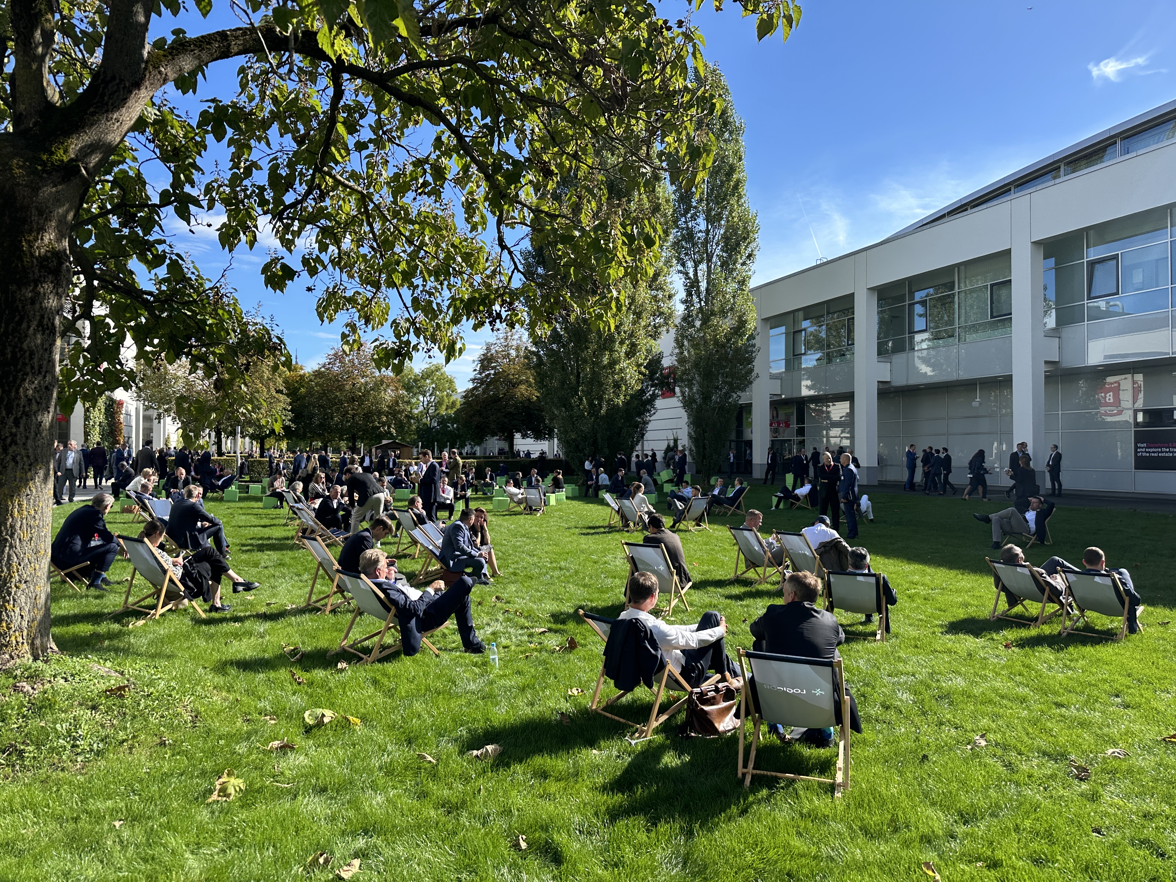 Nach dem Termin ist vor dem Termin – auf der EXPO Real 2024 genießen Fachbesucher die sonnige Auszeit auf der grünen Wiese des Messegeländes. Entspanntes Networking in Liegestühlen | BERLINboxx