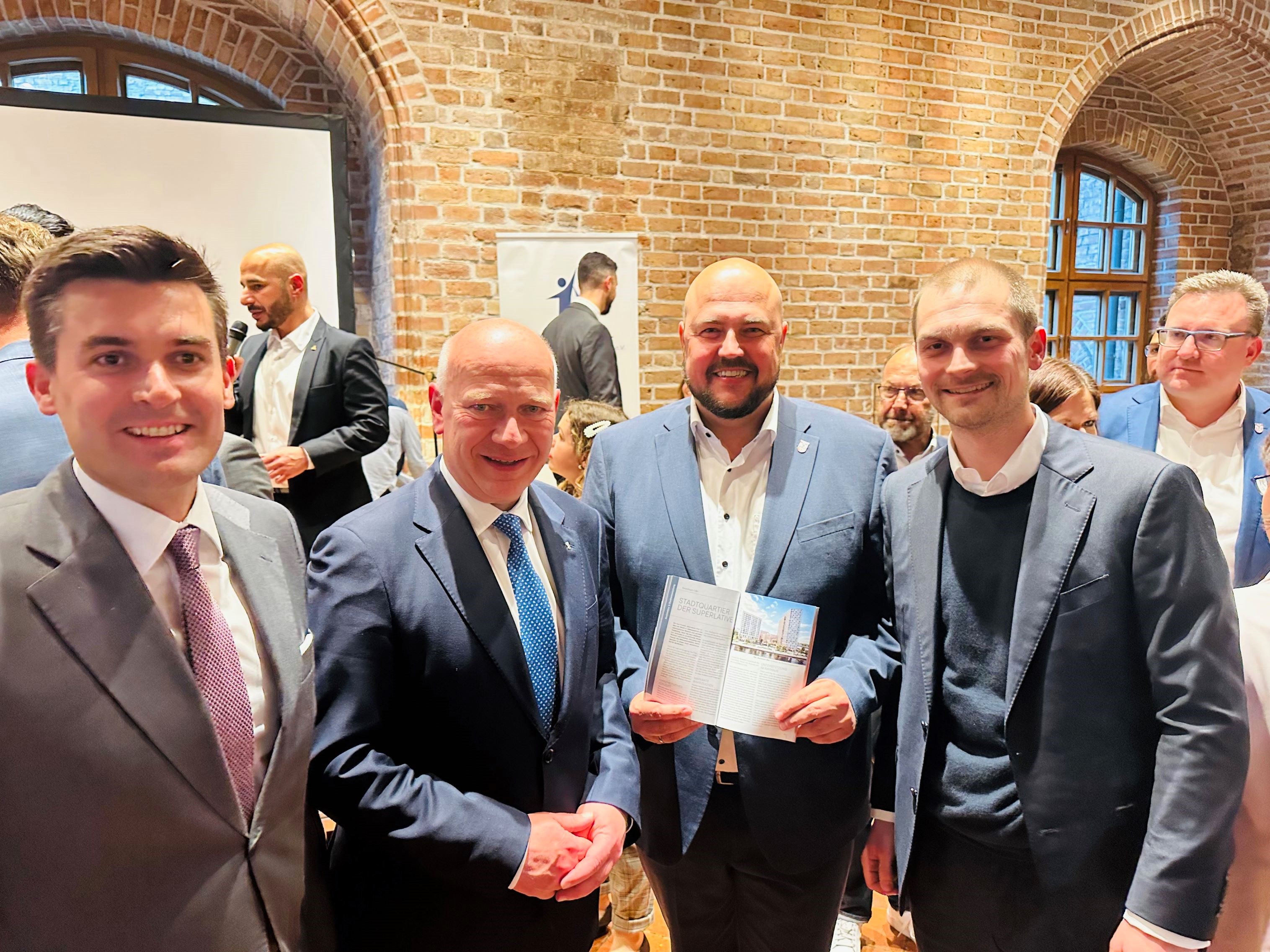 Gäste der Jubiläumsfeier: Carl Fay (rechts) und Manuel Oltersdorf von der FAY Gruppe im  Gespräch mit dem Regierenden Bürgermeister Kai Wegner (2.v.l.) und  Bezirksbürgermeister Frank Bewig (2. v. r.). Die FAY Gruppe ist mit dem  Entwicklungsprojekt „Spandauer Ufer“ in Spandau engagiert – direkt gegenüber von  Rathaus und Bahnhof entsteht hier ein neues, gemischt genutztes Stadtquartier mit Blick  auf die Havel | BERLINboxx